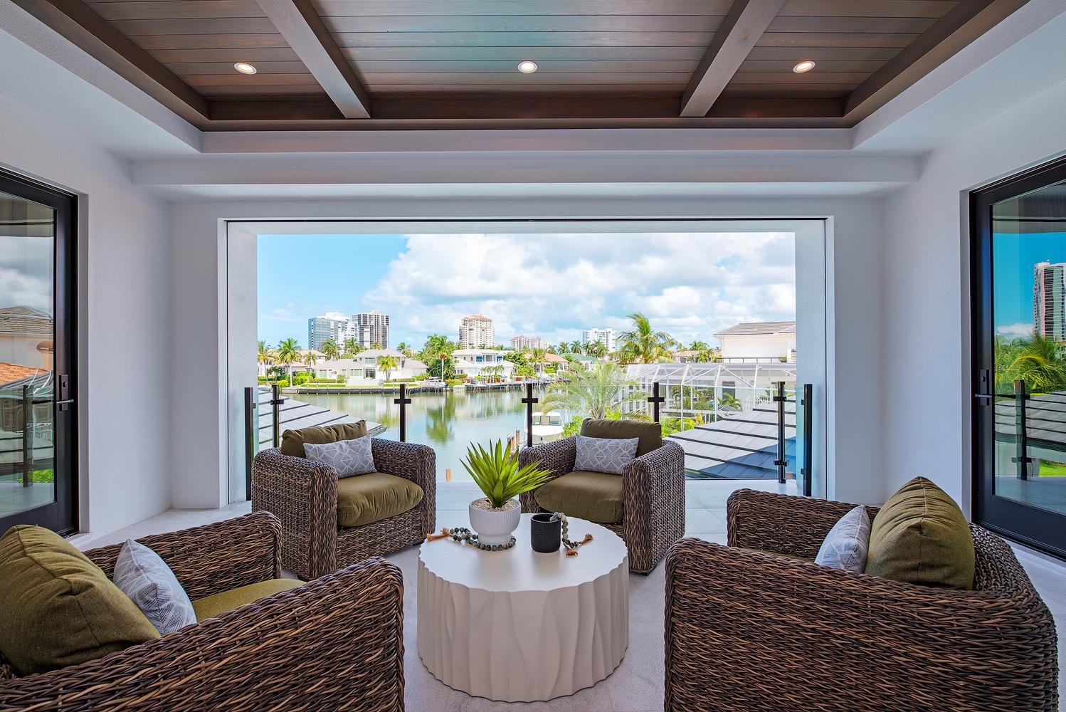 A sheltered balcony with wicker seating framing the waterfront at 405 Neapolitan Way