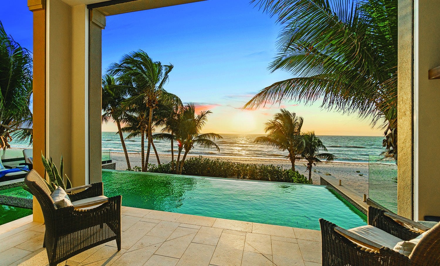 Palm trees framing a Gulf Coast sunset from a pool terrace